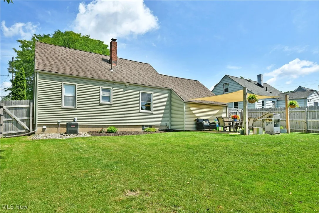 Rear view of property with a chimney, a fenced backyard, and roof with shingles