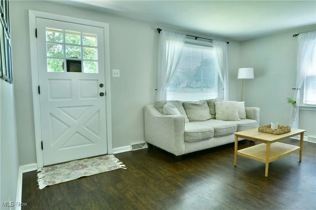 Living area featuring dark wood-style flooring and baseboards