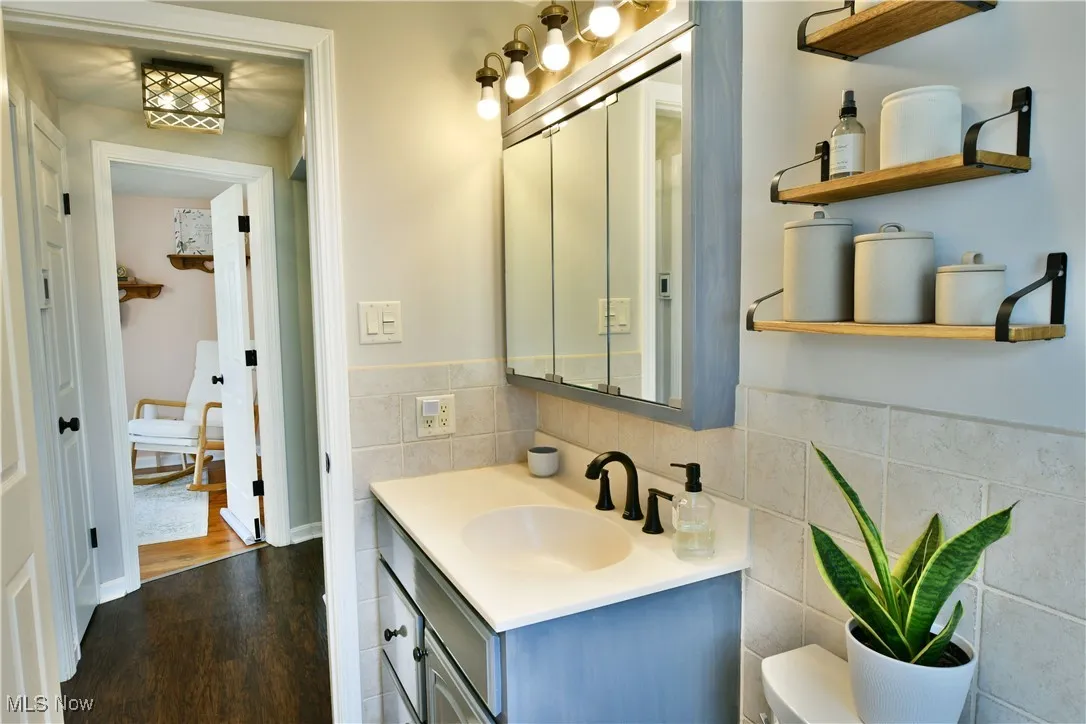 Bathroom with tile walls, vanity, wood finished floors, and wainscoting