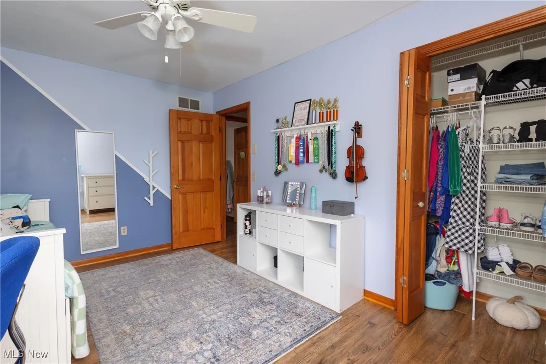 Bedroom with wood finished floors, a closet, and a ceiling fan