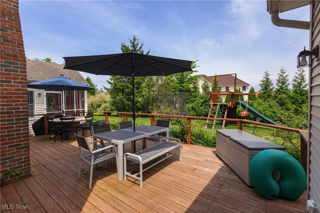 Wooden terrace with outdoor dining area and a playground