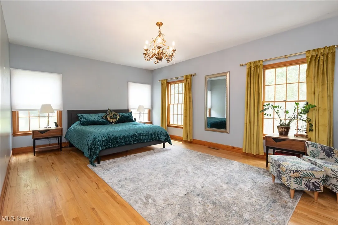 Bedroom featuring a chandelier, multiple windows, and light wood finished floors