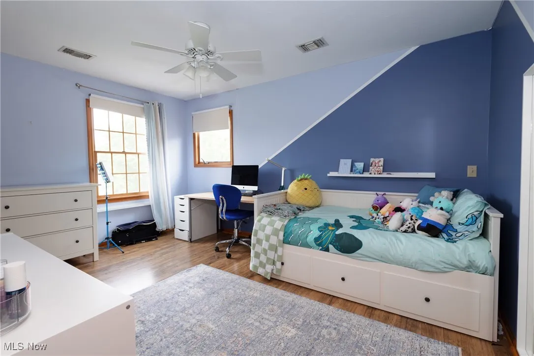 Bedroom with wood finished floors, ceiling fan, and a desk