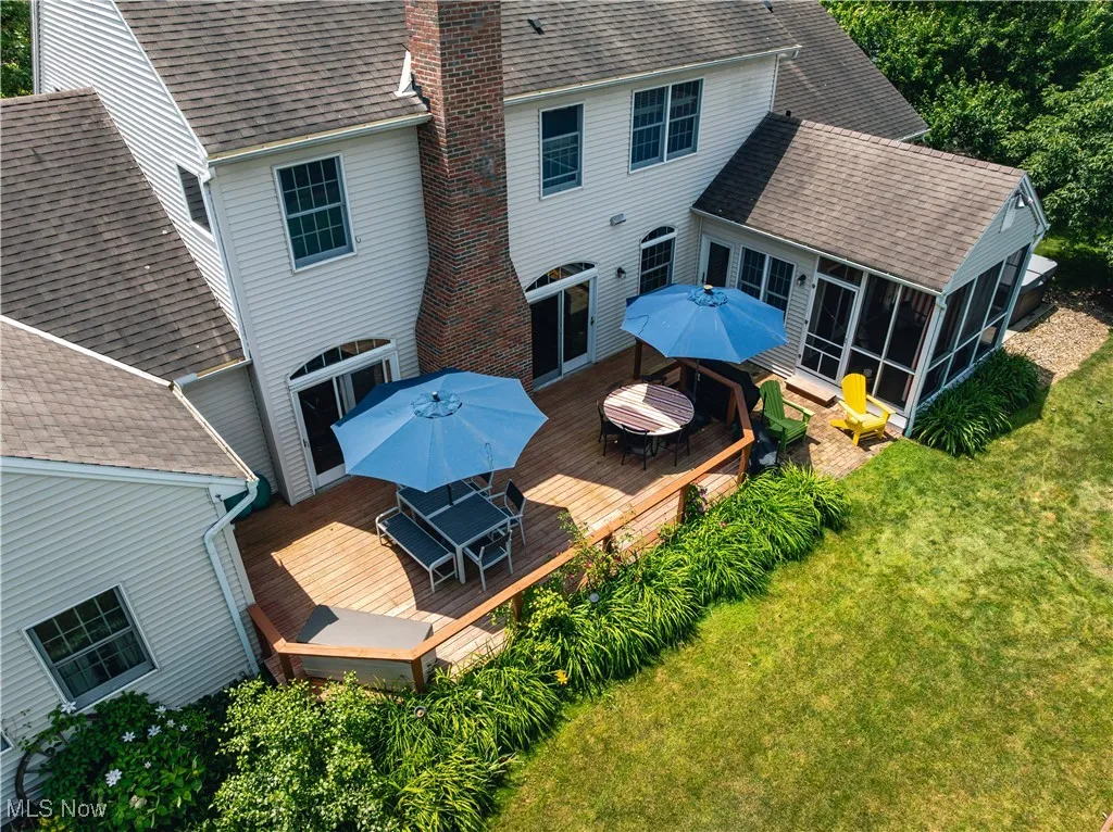 Rear view of house featuring outdoor dining space, a sunroom, a deck, a chimney, and a yard