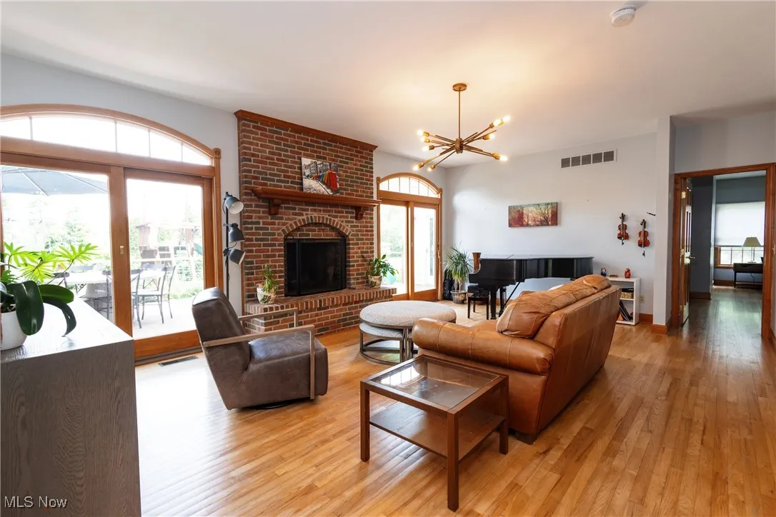 Living room with hardwood flooring, a chandelier, and a wood fireplace.