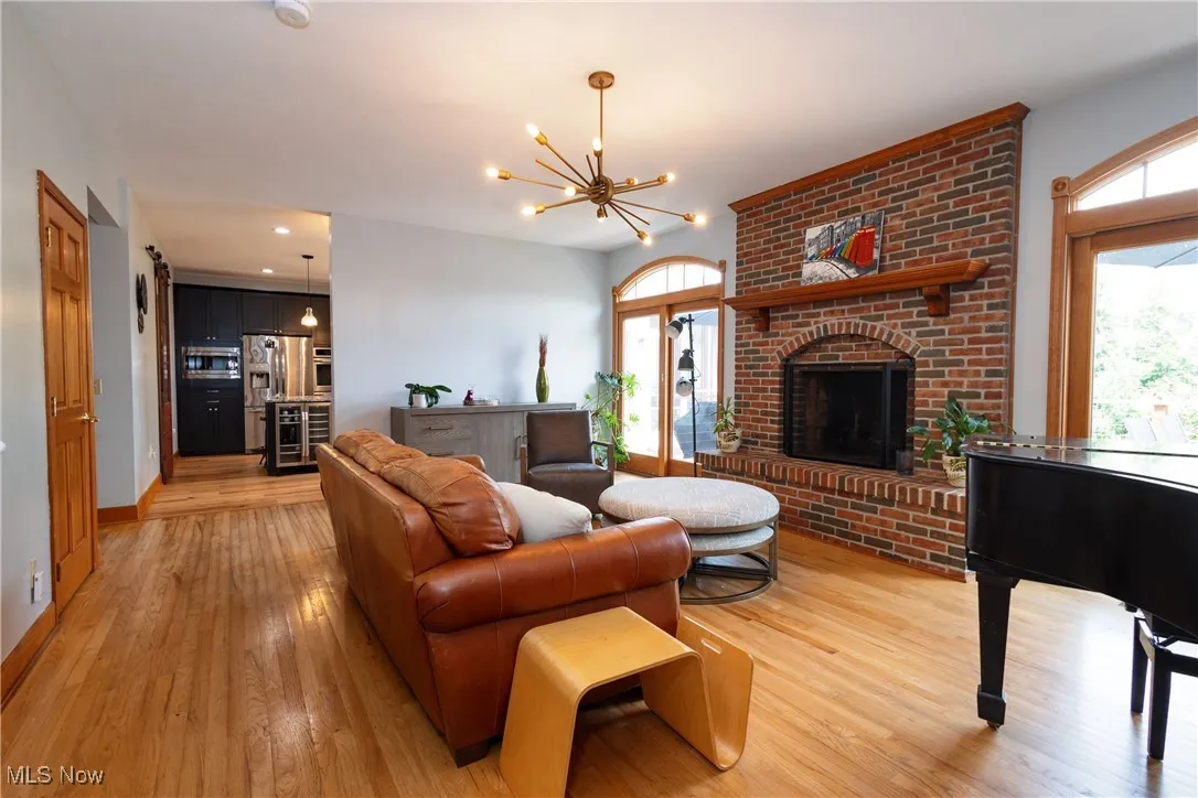 Living room featuring hardwood flooring, a chandelier, a brick fireplace, and recessed lighting