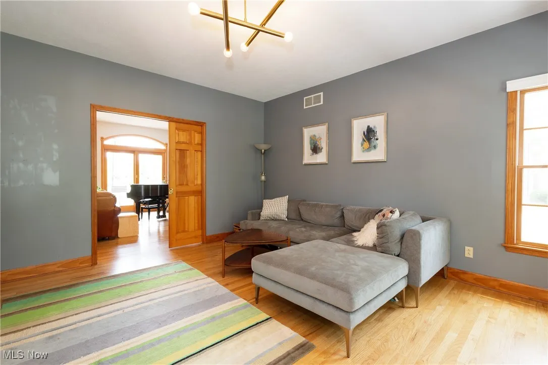 Living room with hardwood flooring, pocket doors and a chandelier