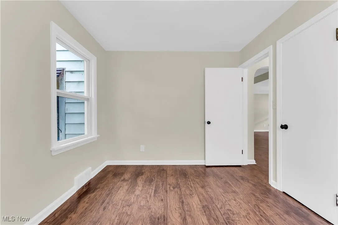 Spare room featuring arched walkways and wood finished floors