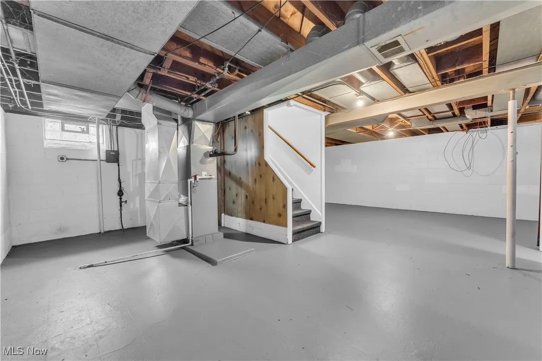 Basement featuring heating unit and stairs
