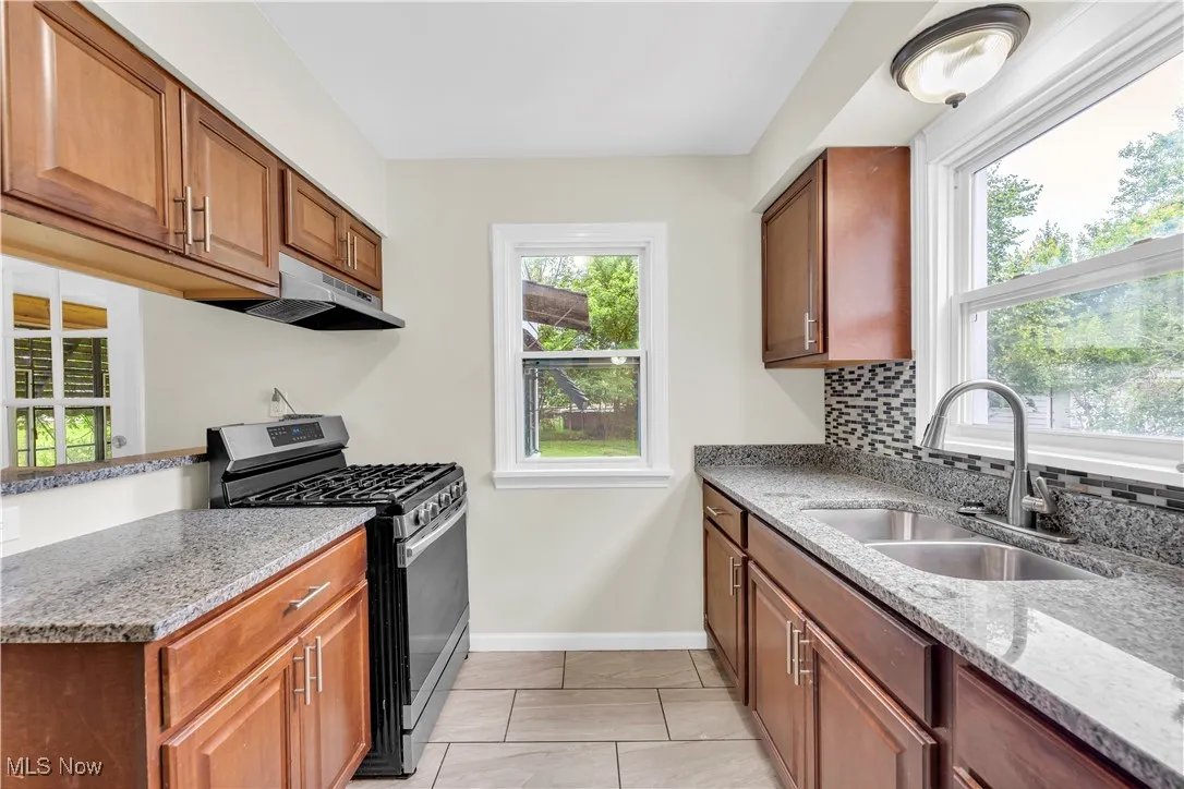 Kitchen with gas range, plenty of natural light, and light stone countertops