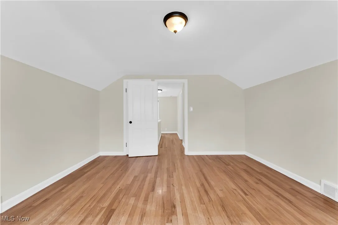 Additional living space featuring lofted ceiling and light wood-style flooring