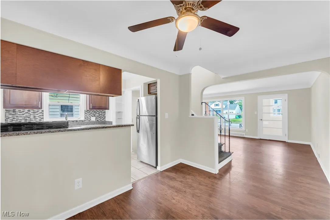 Kitchen featuring freestanding refrigerator, dark countertops, decorative backsplash, light wood finished floors, and ceiling fan