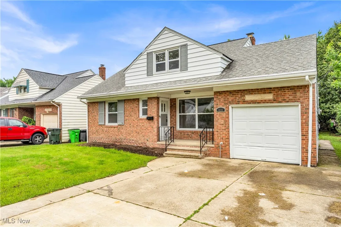 View of front of home featuring brick siding, a front lawn, an attached garage, and driveway