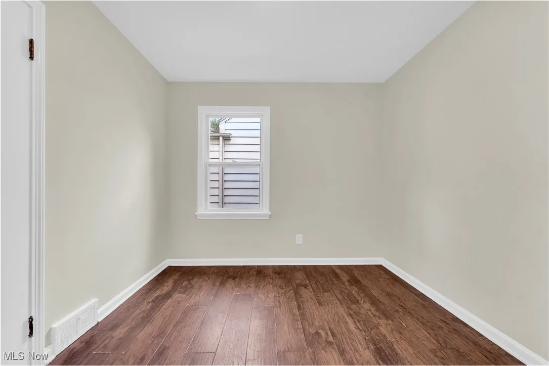 Unfurnished room featuring dark wood-type flooring and baseboards
