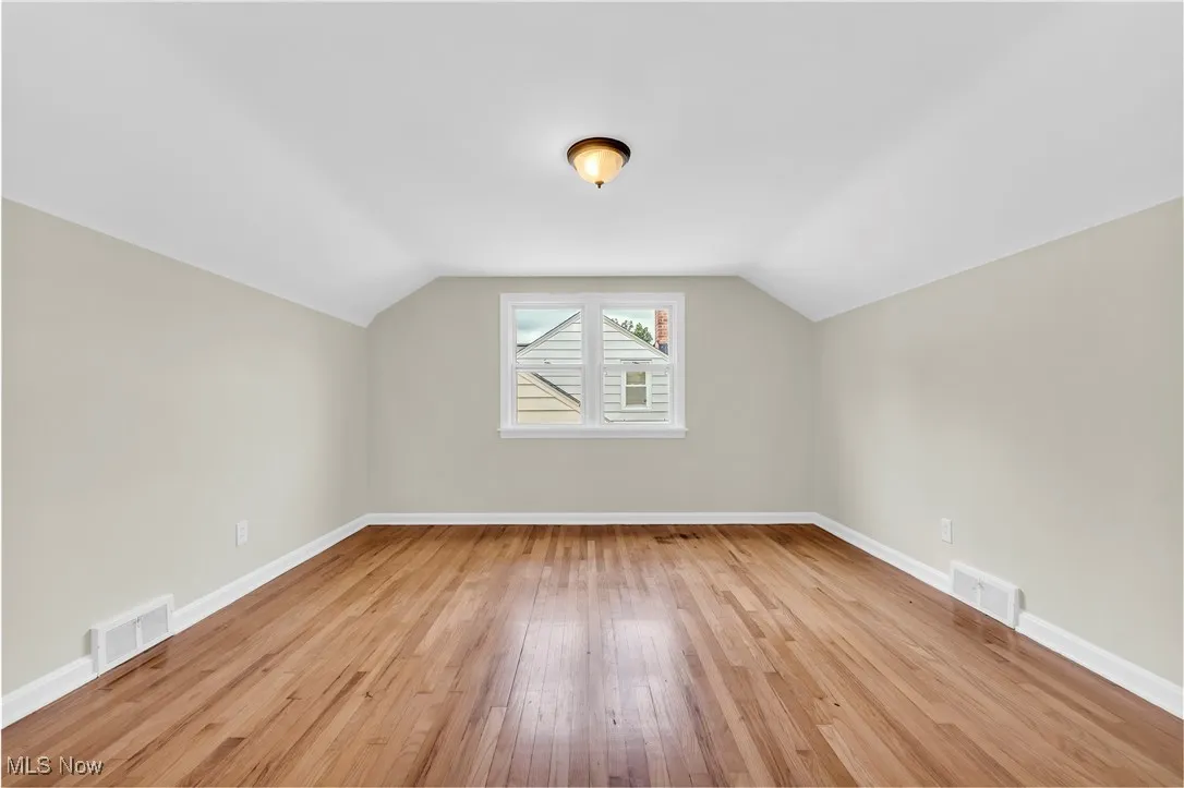 Additional living space featuring light wood-style flooring and vaulted ceiling