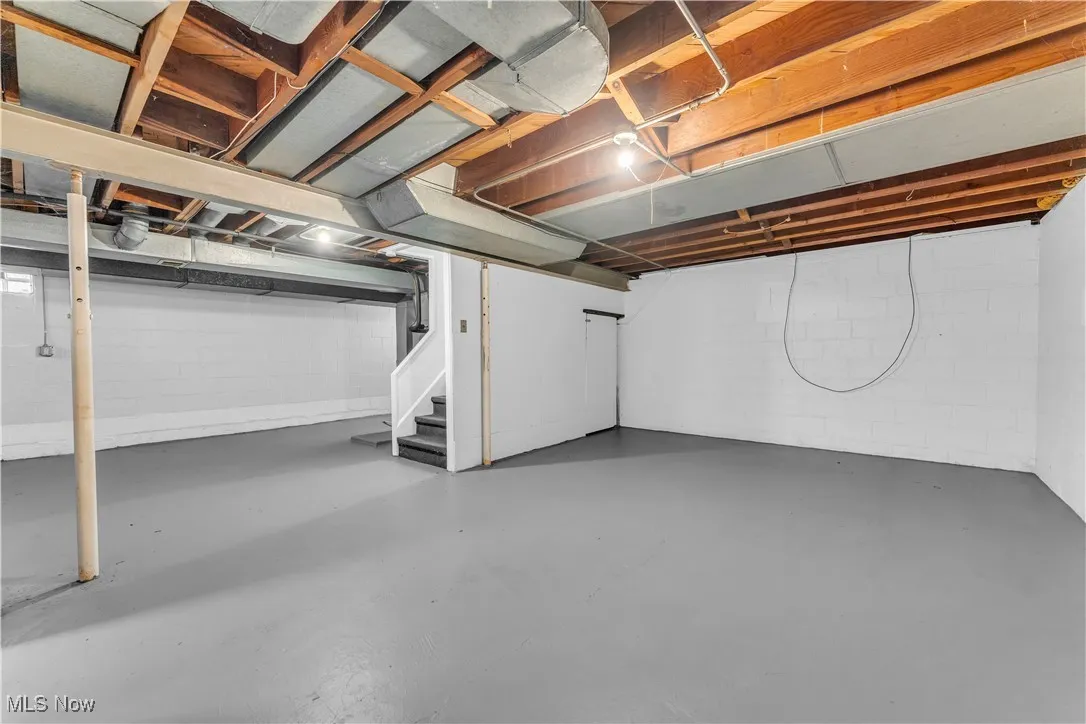 Unfinished below grade area with stairway and concrete block wall