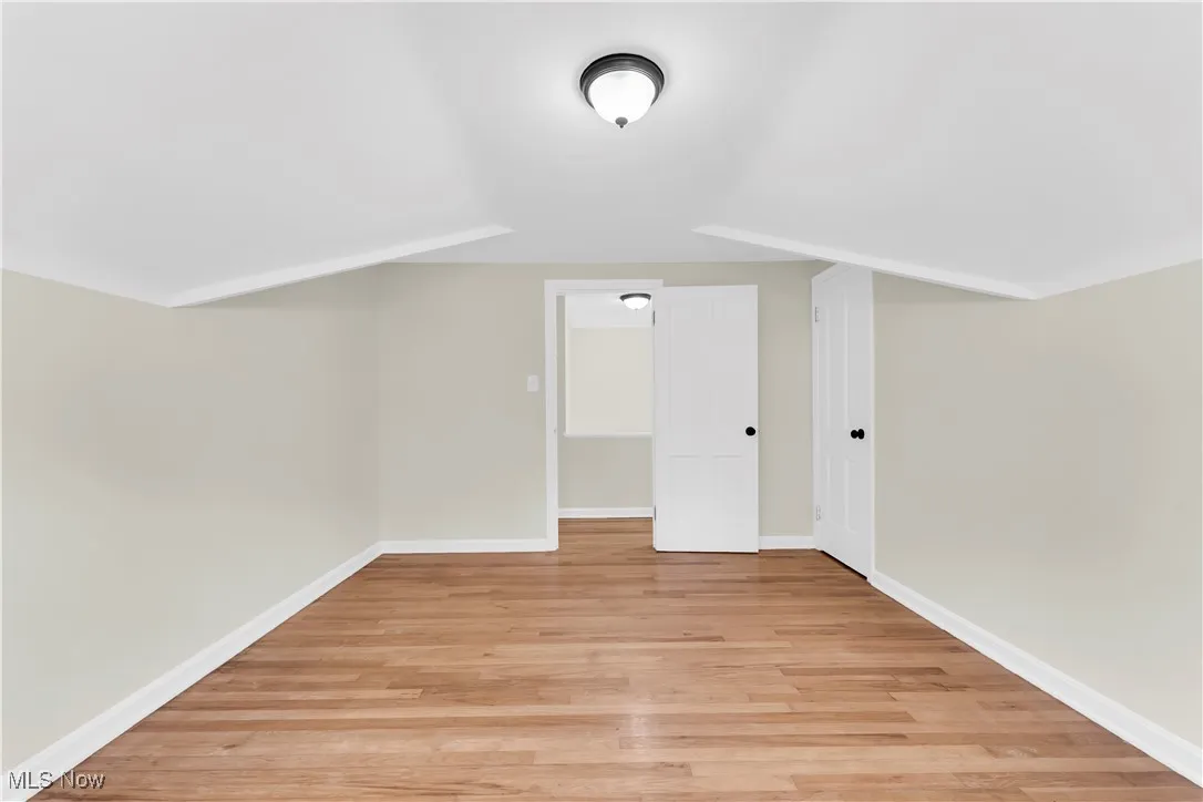 Bonus room with light wood-style flooring and baseboards