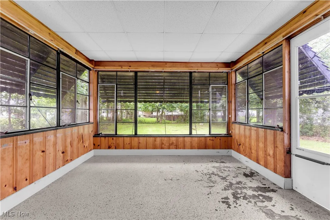 Unfurnished sunroom featuring wood walls