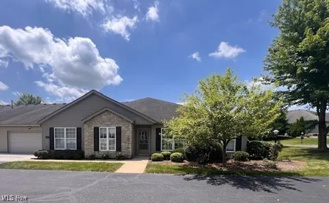 Ranch-style house with an attached garage, driveway, and stone siding