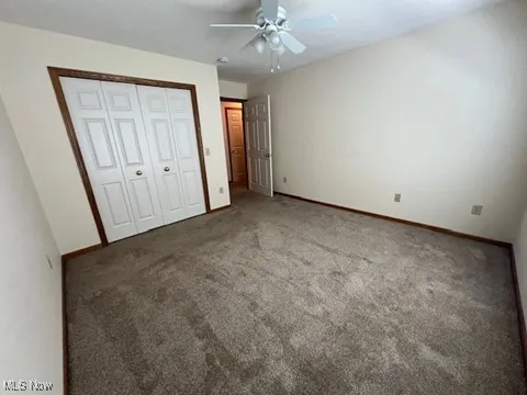 Unfurnished bedroom featuring carpet floors, a closet, and ceiling fan