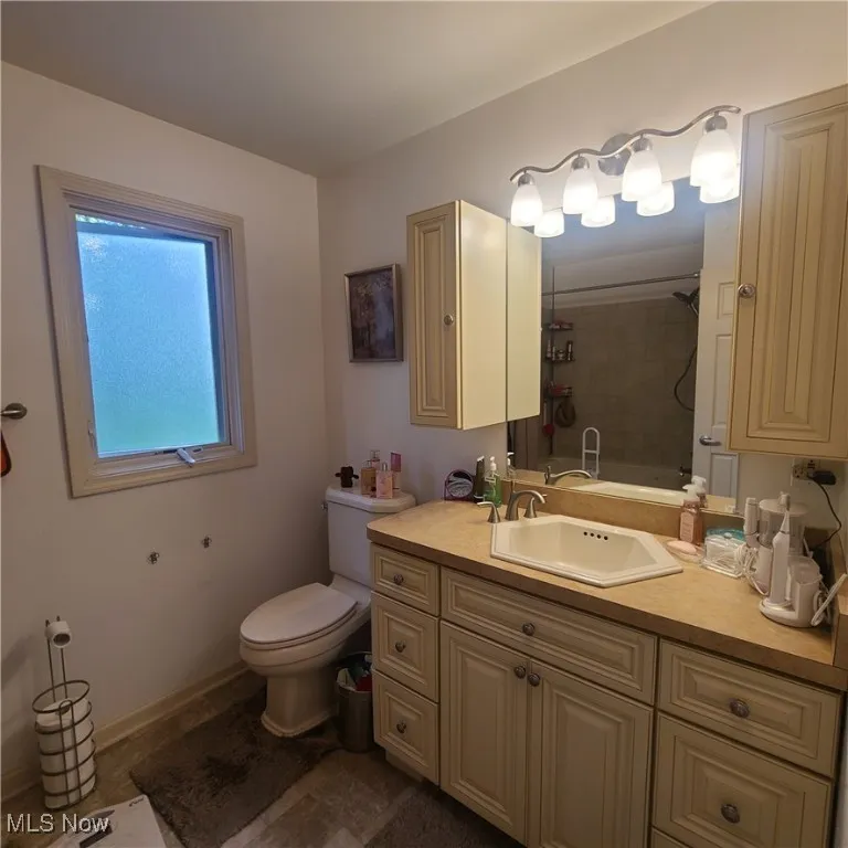 Master Bath with vanity, privacy window, toilet, and shower/jetted tub combination