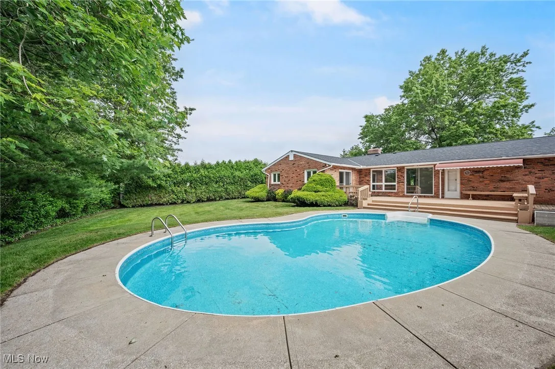 Outdoor pool with a deck and a lawn