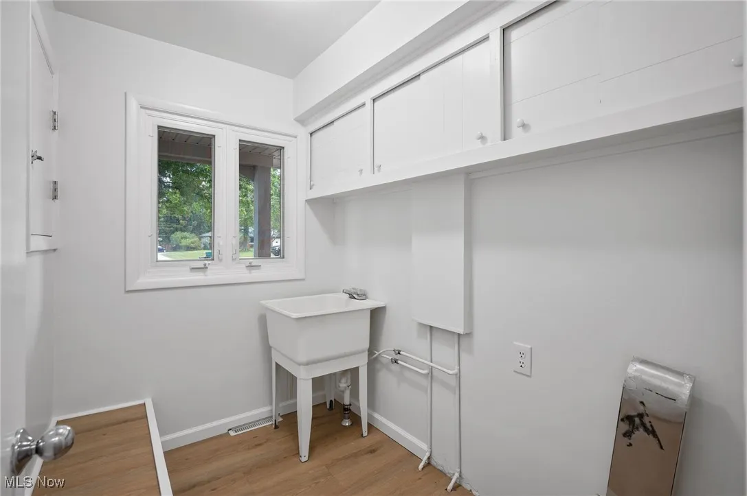 Laundry room featuring light wood-style flooring and cabinet space
