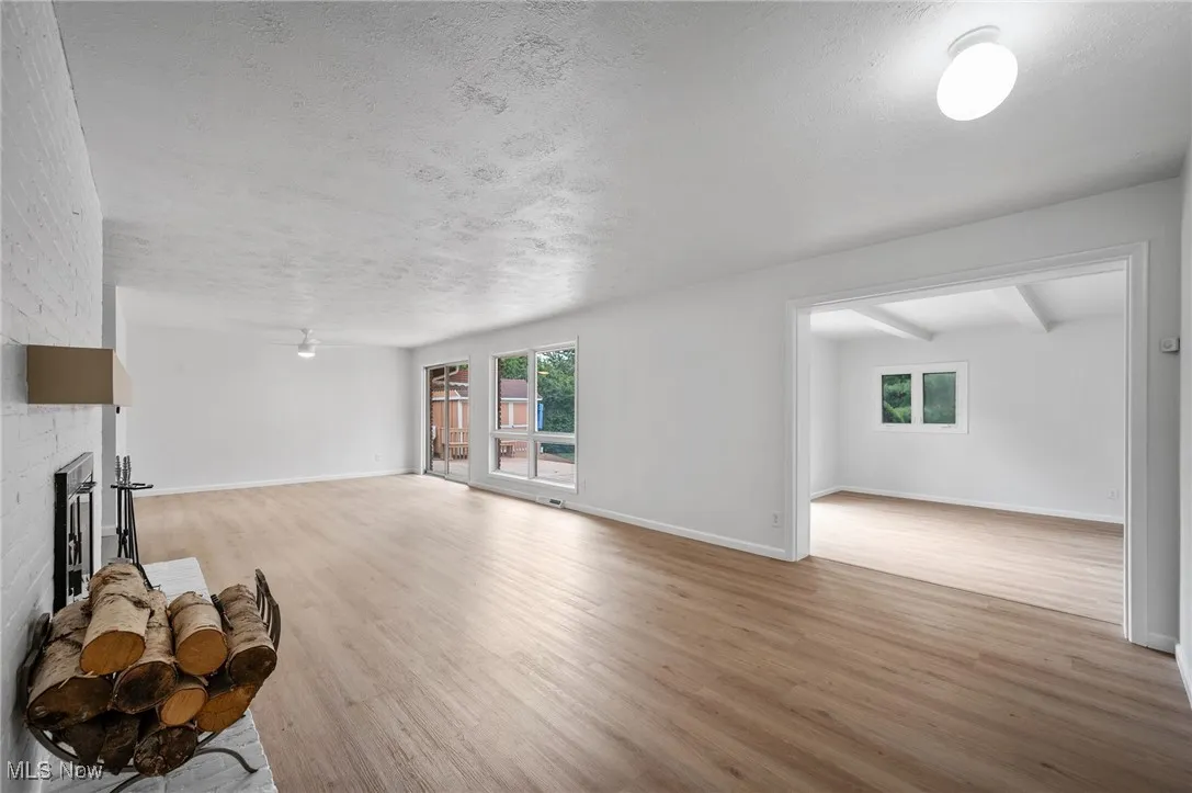 Unfurnished living room with wood finished floors, a textured ceiling, plenty of natural light, and a fireplace