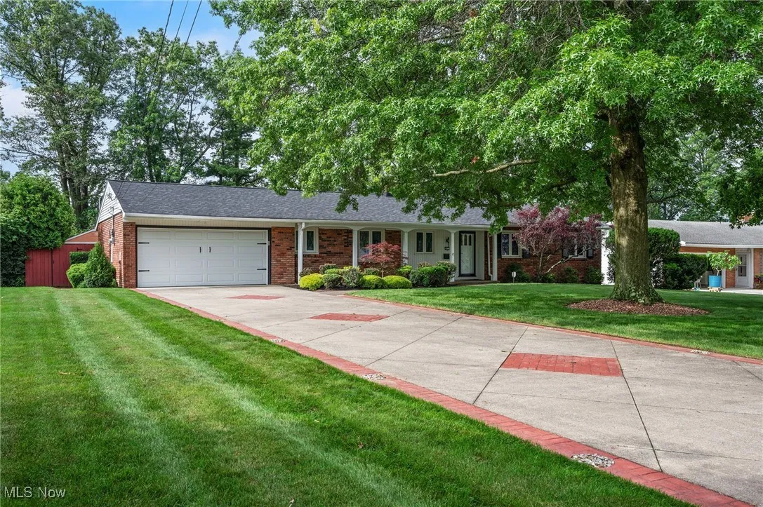 Single story home with brick siding, an attached garage, a front lawn, concrete driveway, and roof with shingles