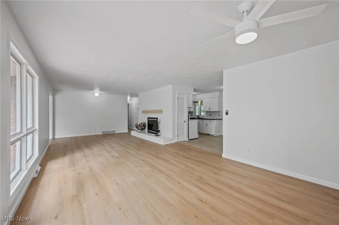 Unfurnished living room featuring a ceiling fan and light wood finished floors
