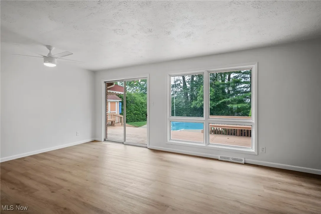 Empty room with wood finished floors, a textured ceiling, and ceiling fan