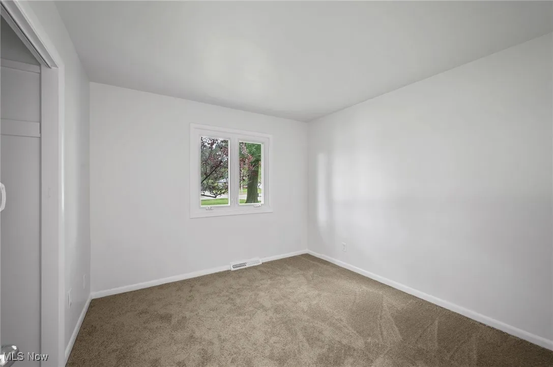 Spare room featuring carpet and baseboards