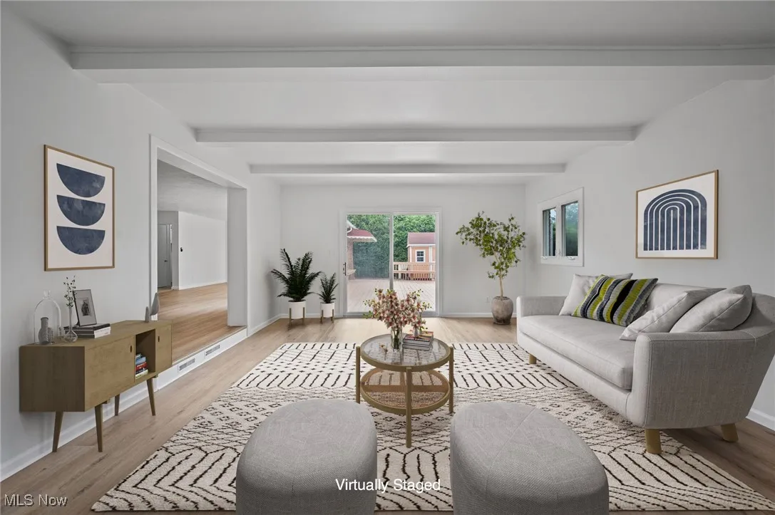 Living area with light wood-style flooring and beam ceiling