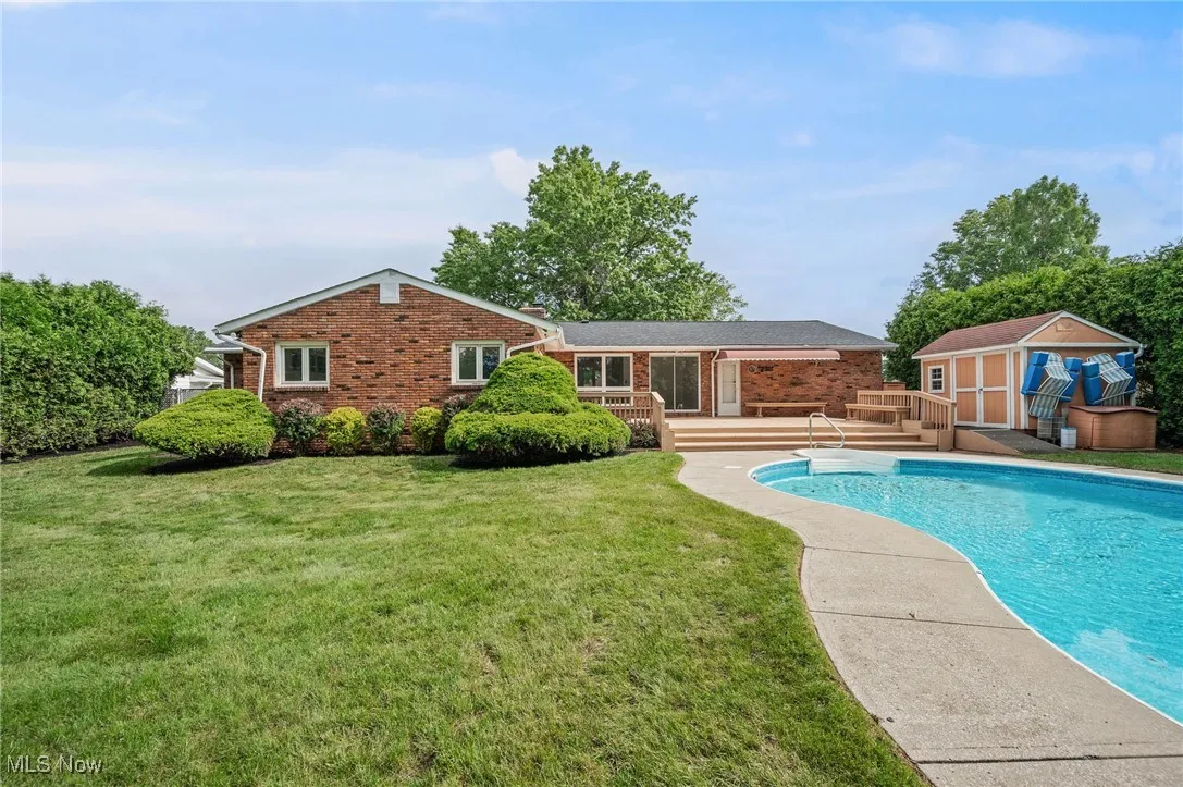 Swimming pool with a wooden deck, a storage unit, and a yard