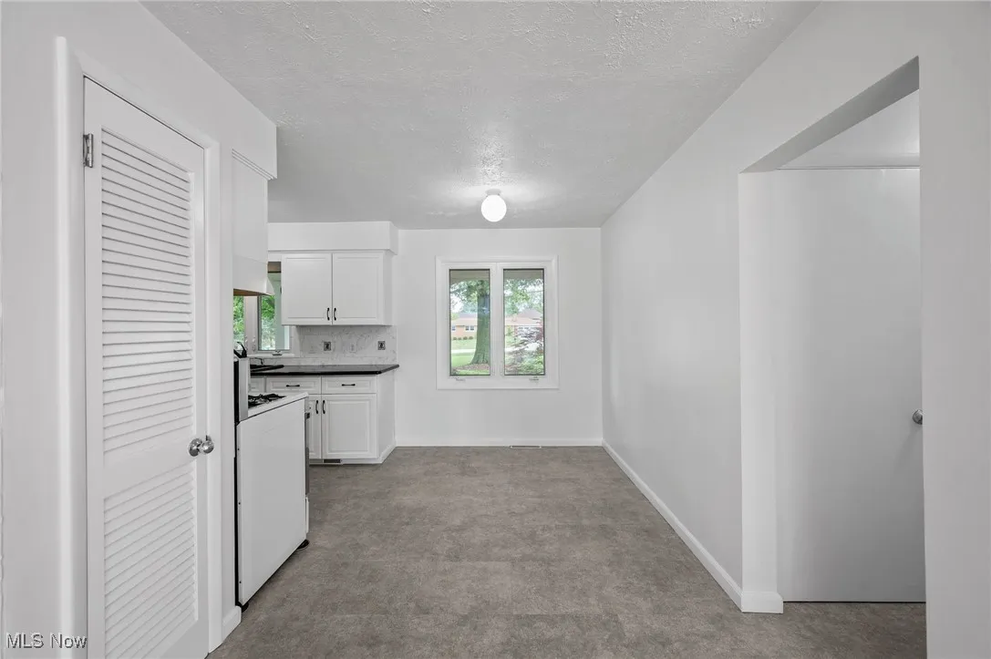 Kitchen featuring carpet flooring, white cabinets, white stove, a textured ceiling, and premium range hood