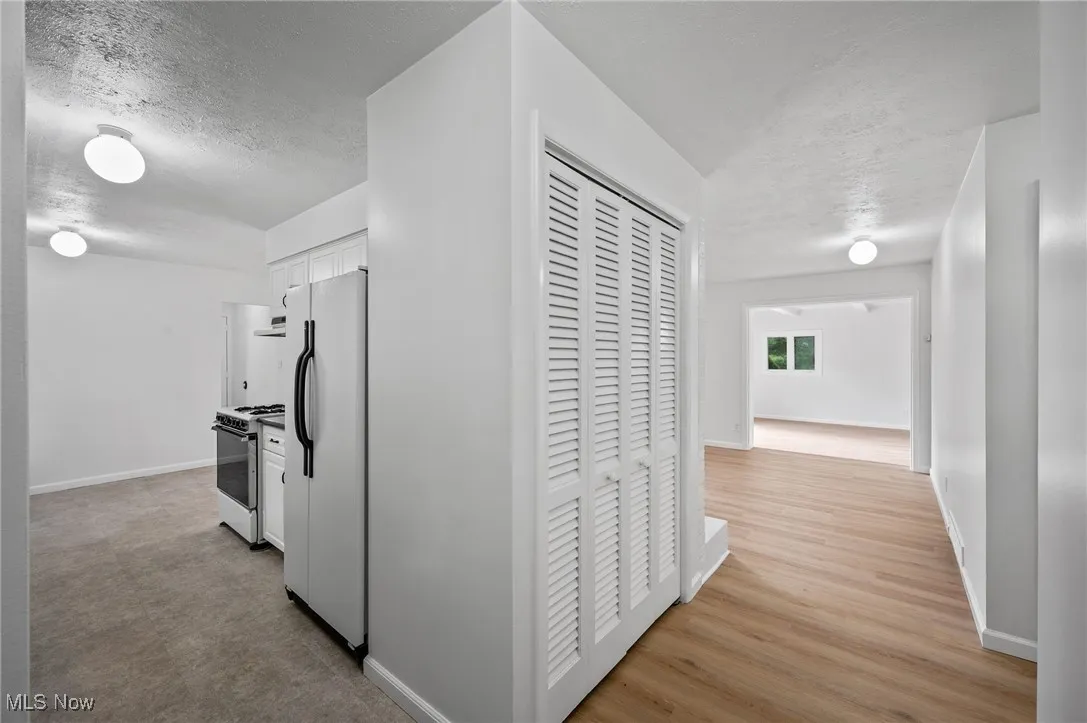 Hall with a textured ceiling and light wood-type flooring