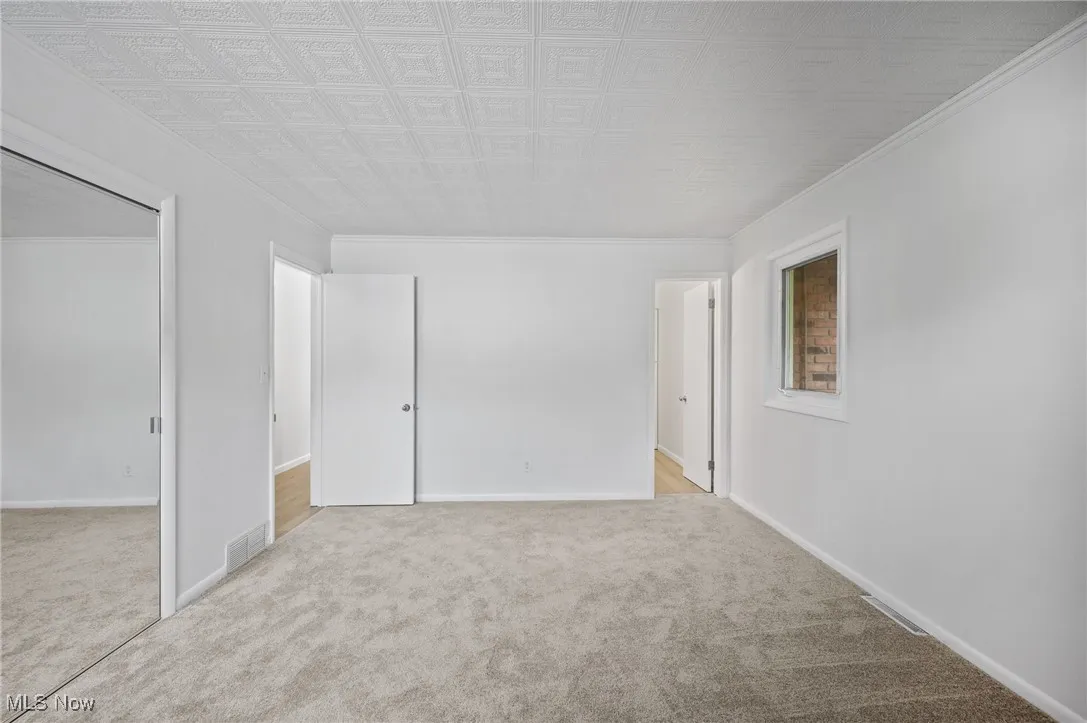 Carpeted empty room featuring crown molding and baseboards