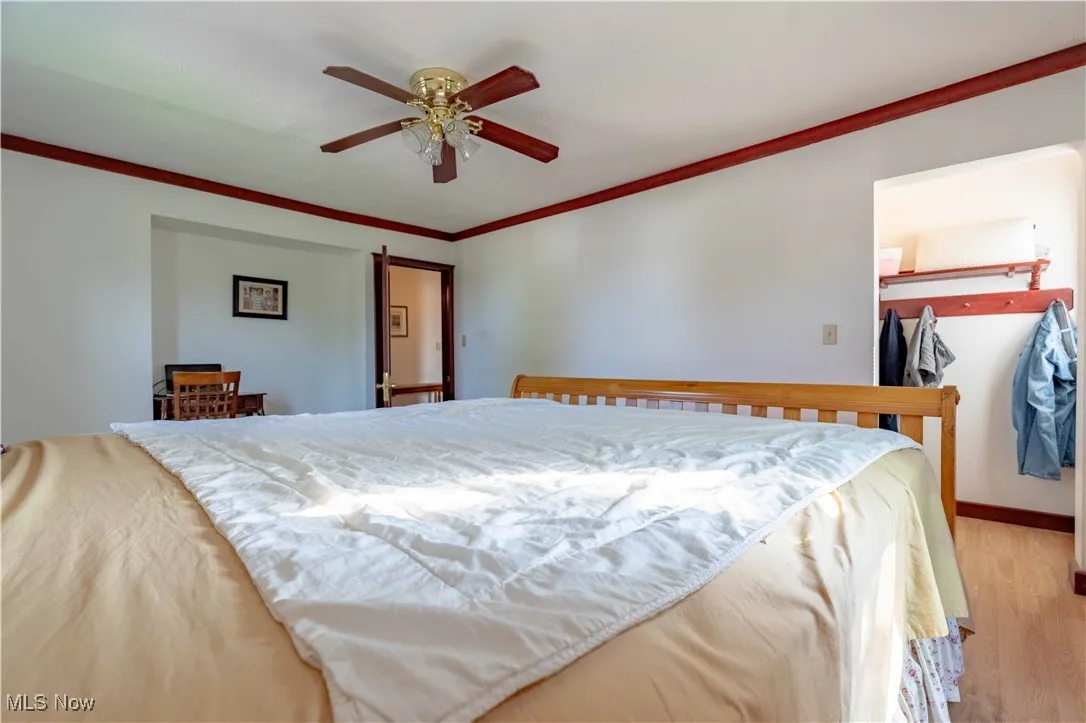 Bedroom featuring light wood-style flooring, ornamental molding, and ceiling fan