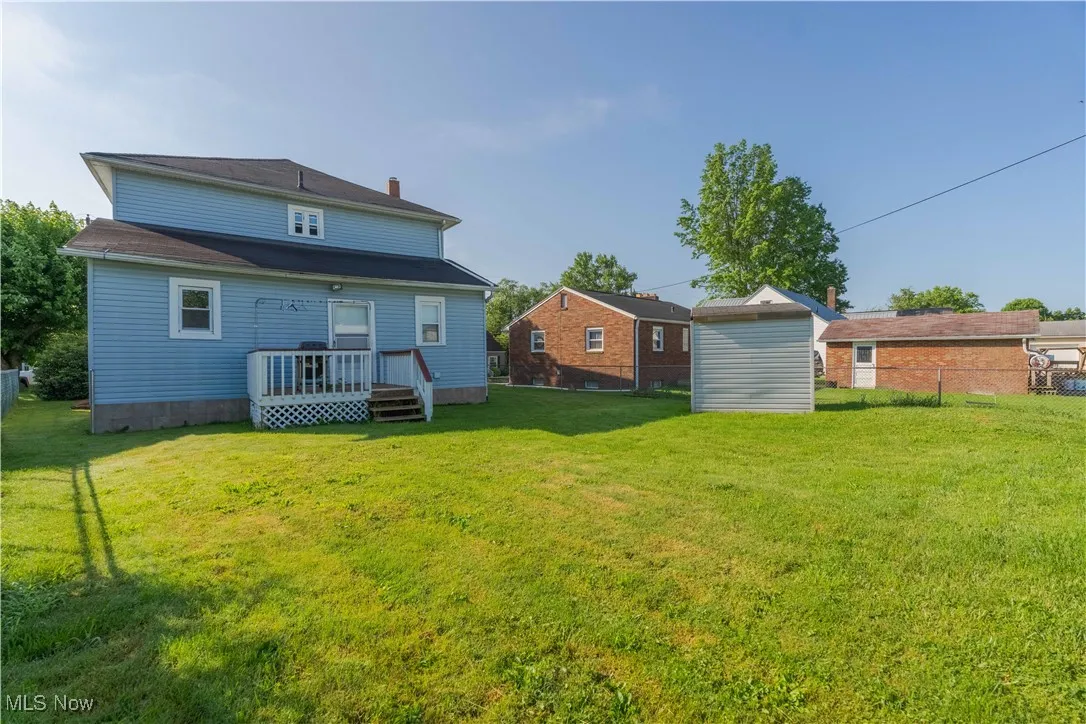 Rear view of house featuring a storage unit and a wooden deck