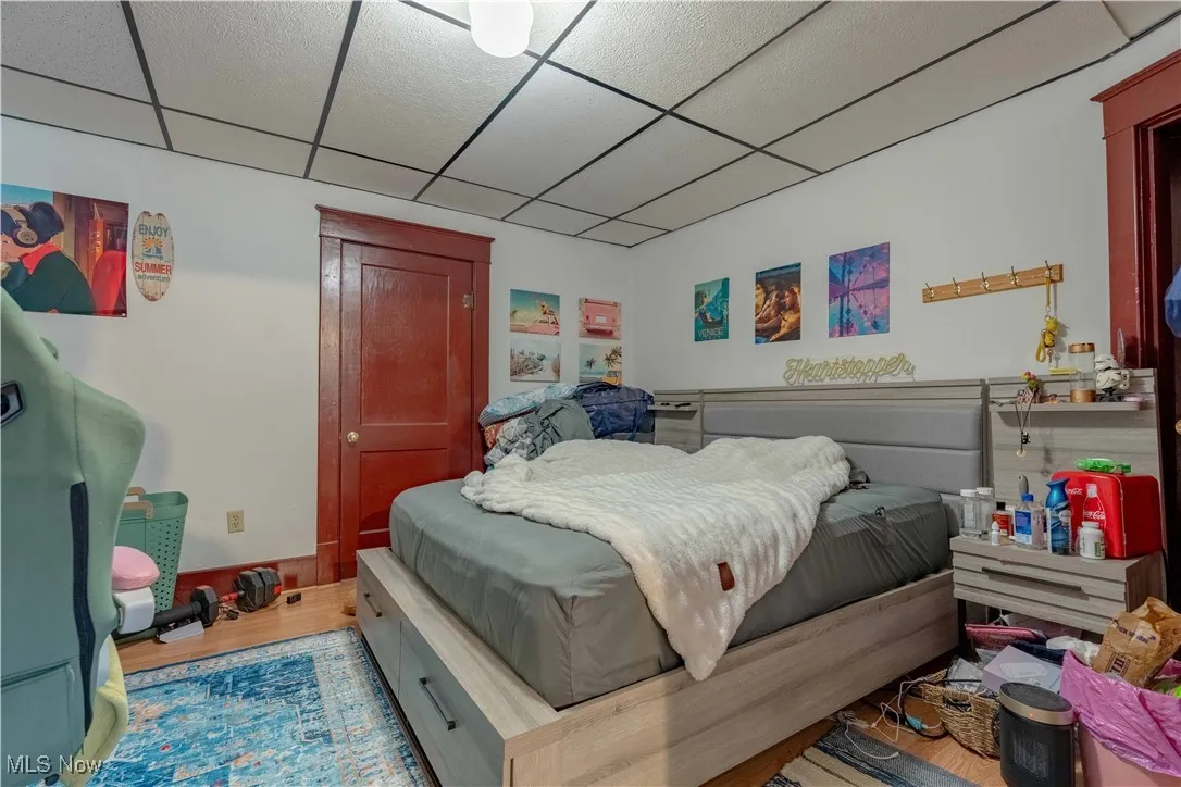 Bedroom with wood finished floors and a paneled ceiling