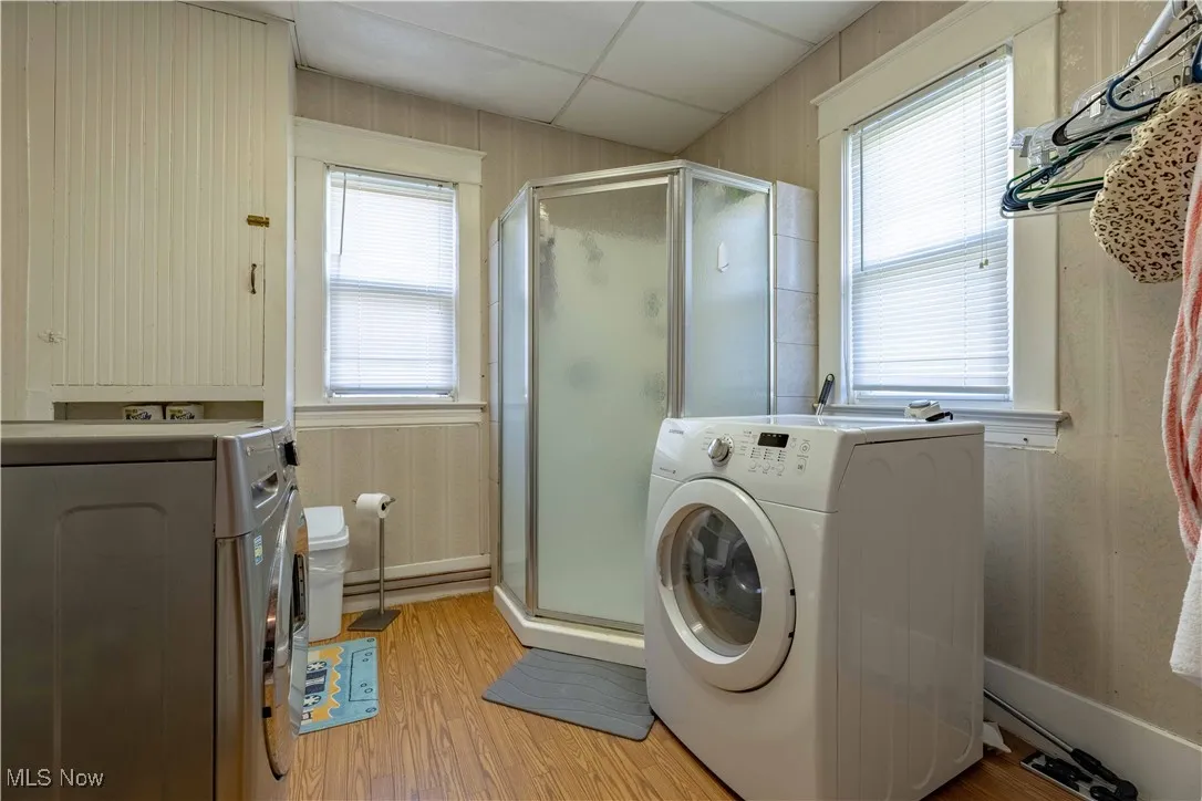 Washroom with light wood finished floors, washer and dryer, and plenty of natural light