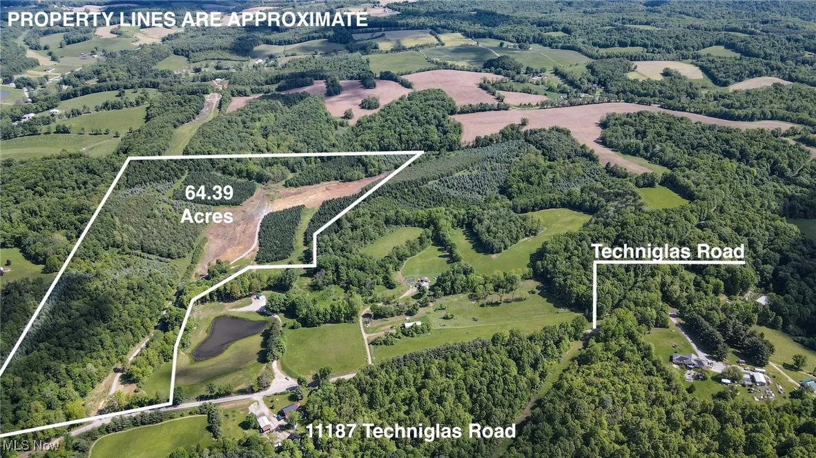 Aerial view of property and surrounding area featuring property parcel outlined and a forest