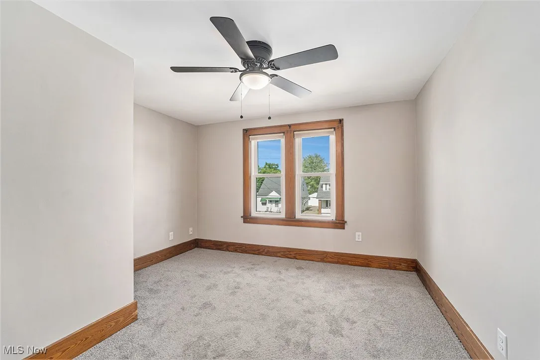 Carpeted spare room with baseboards and a ceiling fan