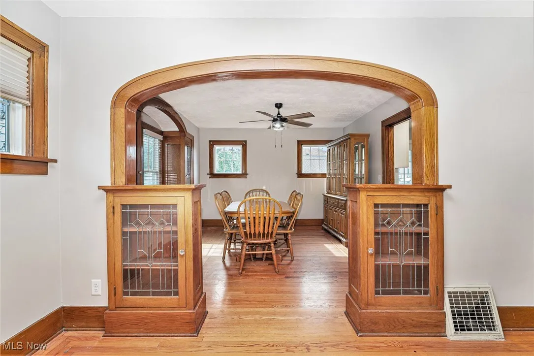 Dining space featuring arched walkways, light wood-style flooring, and a ceiling fan