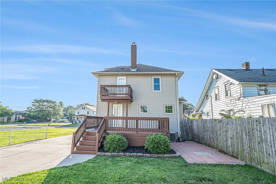 Rear view of property with a balcony, a fenced backyard, a deck, and a chimney