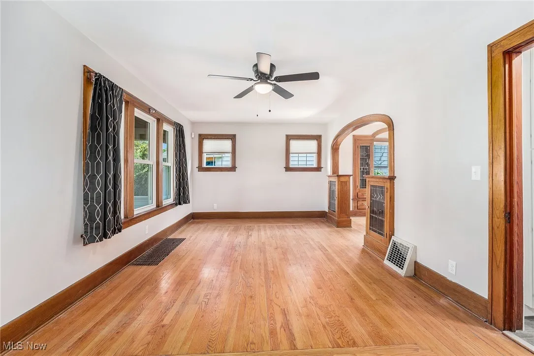 Spare room featuring light wood-type flooring, a ceiling fan, and arched walkways