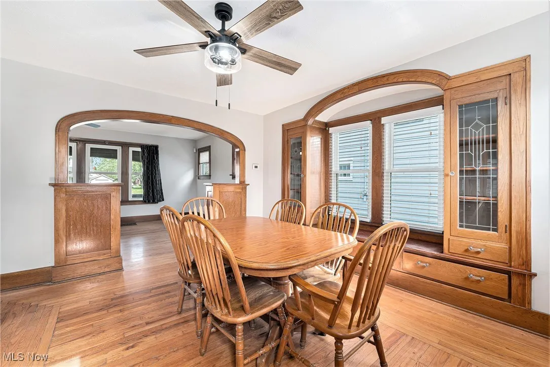 Dining space with arched walkways, a ceiling fan, and light wood-type flooring