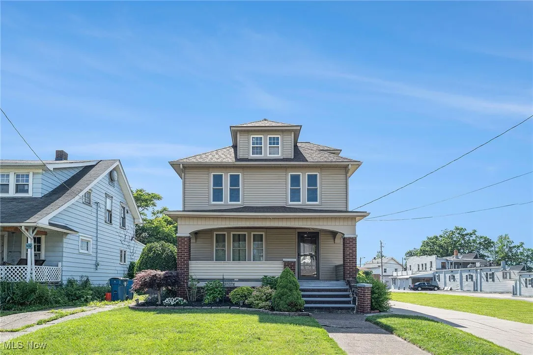 Traditional style home with covered porch, a front lawn, and roof with shingles