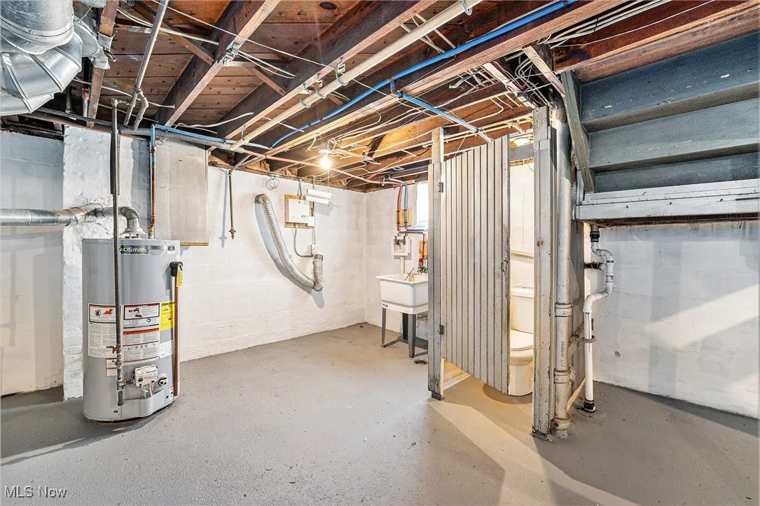 Unfinished basement with gas water heater and a sink