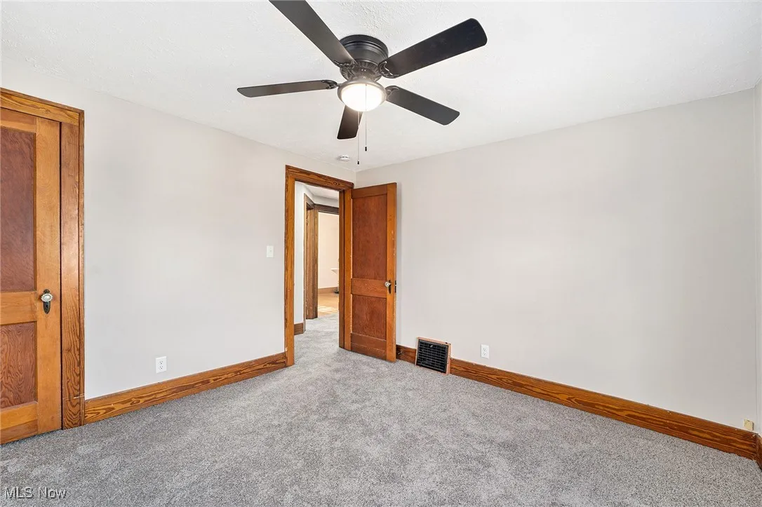 Empty room with carpet floors and ceiling fan